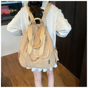 Detailed back view of model wearing a beige casual backpack with adjustable straps