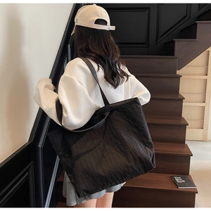 Close-up of a large black tote bag with a unique pleated texture on minimalist stairs