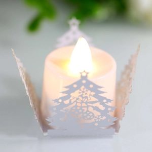 Détail d'une bougie LED vacillant à travers un abat-jour en papier découpé au laser sapin