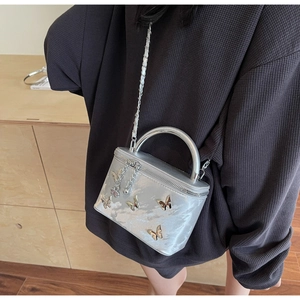 Silver bow-accented handbag with crossbody chain strap worn on grey waffle hoodie
