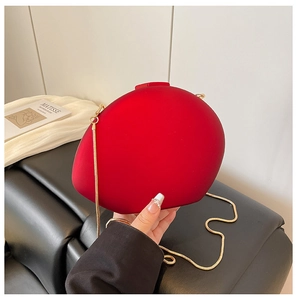 Détail du sac en acrylique rouge en forme de galet avec chaîne dorée et fermoir carré