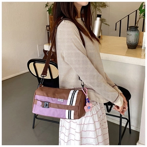 Gros plan du sac bandoulière en nylon à carreaux avec breloque fleurie sur un mannequin