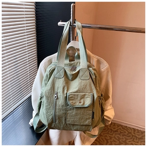 Detail of light green nylon backpack showing waterproof fabric and versatile side pockets