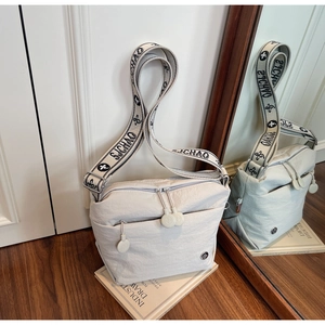 Detail view of off-white canvas crossbody bag with jacquard wide strap and double zippers
