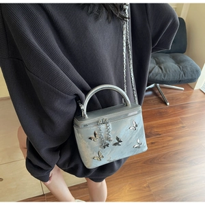 Close-up of silver bow crossbody bag featuring metallic butterfly details and chain strap
