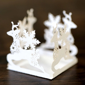Detailed laser-cut white cardstock with Christmas reindeer and snowflake hollow patterns