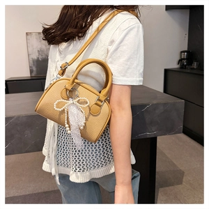 Detail of yellow lychee texture leather Boston bag with pearl chain and lace bow charm