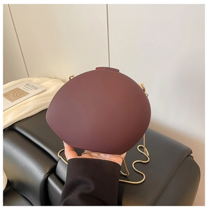 Détail du sac de soirée rond en acrylique mat bordeaux avec bandoulière chaîne dorée