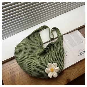Détail d'un sac hobo tressé vert avec une fleur de marguerite blanche en crochet 3D