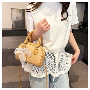 Close-up of beige lychee texture bag with elegant lace bow and pearl pendant details
