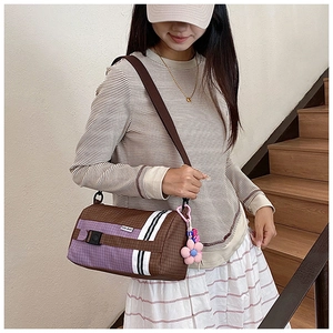 Détail du sac polochon en nylon à carreaux avec sangle rayée et breloque fleur rose