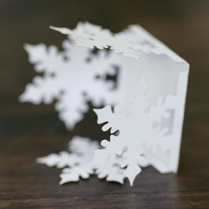 Detail of white laser-cut snowflake paper candle holder with intricate hollow patterns