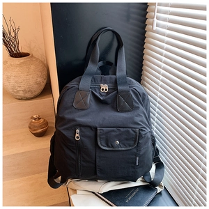 Detail of black nylon travel backpack showing utility pockets and sturdy metal zippers