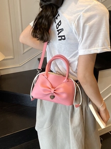 Sac seau rose avec nœud, pendentif cœur et cordon, porté dans un cadre moderne
