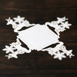 Detail of laser-cut white pearlescent paper card with reindeer and snowflake patterns