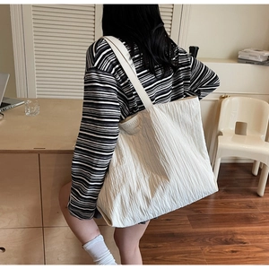 Detail of white tote bag showing pleated fabric texture and brand logo for daily commute