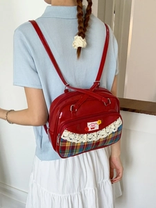 Red retro backpack featuring white lace trim and cherry plaid pocket accents