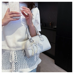 Detail of lychee textured handbag featuring pearl bow and lace ribbon decorations