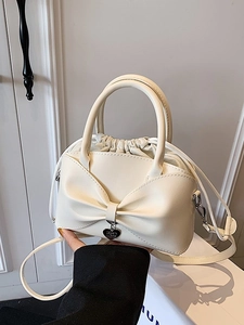Sac seau chic à nœud crème avec pendentif cœur présenté comme sac à main élégant