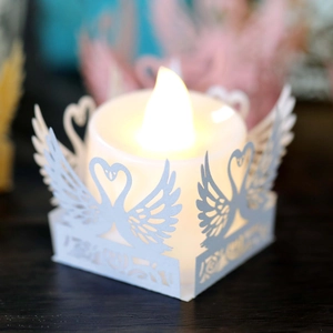 Detail of laser-cut swan heart paper lamp cover with warm glowing LED candle light