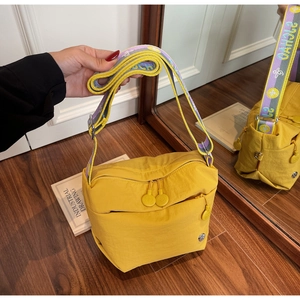 Detail view of bright yellow nylon crossbody bag with geometric pattern wide strap