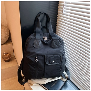 Close-up of black multi-pocket travel backpack with dual handles and fabric logo detail