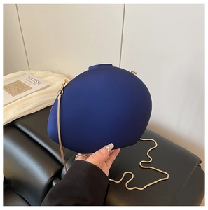 Détail du sac de soirée rigide bleu foncé avec sa bandoulière élégante en chaîne dorée