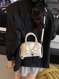 Sac seau crème avec nœud et breloque cœur porté élégamment en bandoulière de dos