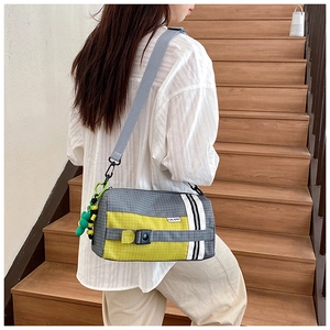 Détail du sac bandoulière en nylon à carreaux gris avec accents jaunes et charm vert