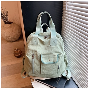 Detail view of the light green nylon backpack showing texture and functional metal buckle