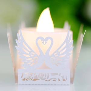Detailed view of white laser-cut paper candle sleeve with elegant swan heart and rose patterns