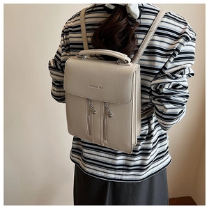 Minimalist beige PU leather backpack with silver zippers shown on model for size scaling