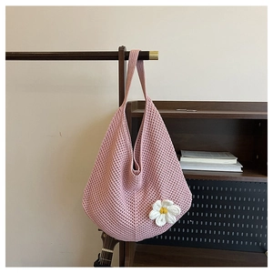 Détail du sac cabas rose tissé avec une marguerite 3D suspendu sur un cintre en bois