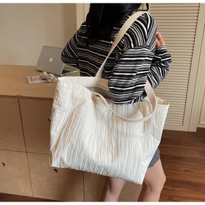 Detail of white pleated tote bag showing large capacity and unique wrinkled fabric texture