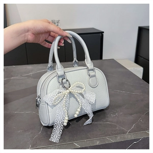 Detail of grey lychee leather Boston bag with lace and pearl bow charm on handle