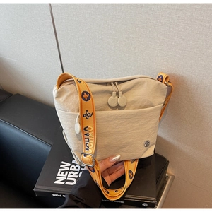 Detailed shot of beige nylon crossbody bag with bright orange jacquard shoulder strap