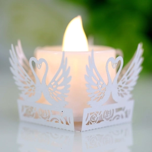 Intricate laser-cut paper candle holder with elegant white swan and rose floral patterns