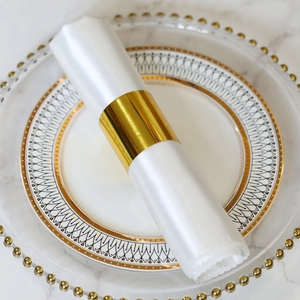 Polished gold metal napkin ring with luxury white satin cloth on marble table