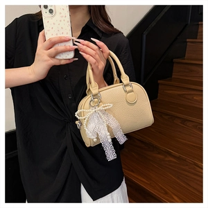 Close-up of beige lychee texture leather Boston bag with lace pearl bow decoration