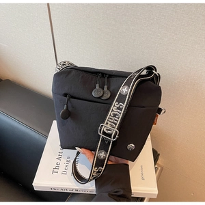 Detail view of the black nylon crossbody bag featuring a wide jacquard woven shoulder strap