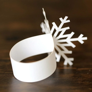 White snowflake paper napkin ring with laser-cut design for Christmas table setting