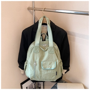 Detail of light green nylon multi-functional backpack with front pockets and top handles