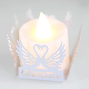 Detailed view of laser-cut paper swan lamp cover over a cylindrical LED candle light