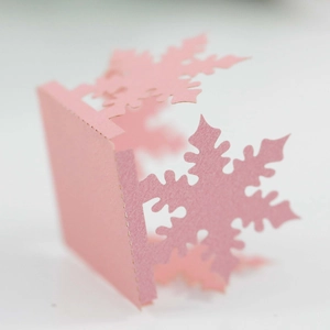 Macro shot of laser-cut pink snowflake favor box with delicate hollow pattern