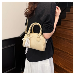 Detail of beige litchi grain Boston bag featuring elegant pearl and lace charm decoration