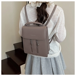 Détail du sac à dos en cuir PU gris Morandi avec pendentif chaîne et lettrage mode