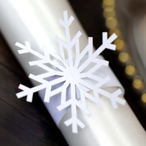 Macro shot of white snowflake napkin ring with precise laser cut design on wood surface