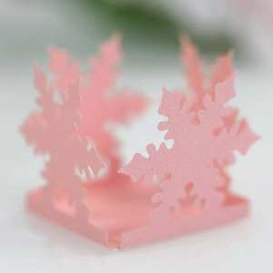 Macro shot of laser-cut pink snowflake paper decoration with fine hollow-out details