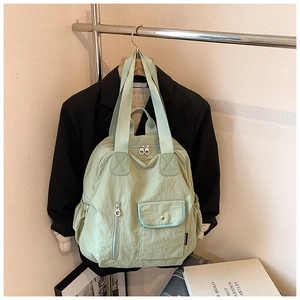 Detail view of the mint green nylon backpack with front vertical zippers and side pockets