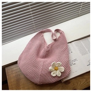 Détail du sac à bandoulière en tricot rose avec fleur 3D sur une surface en bois